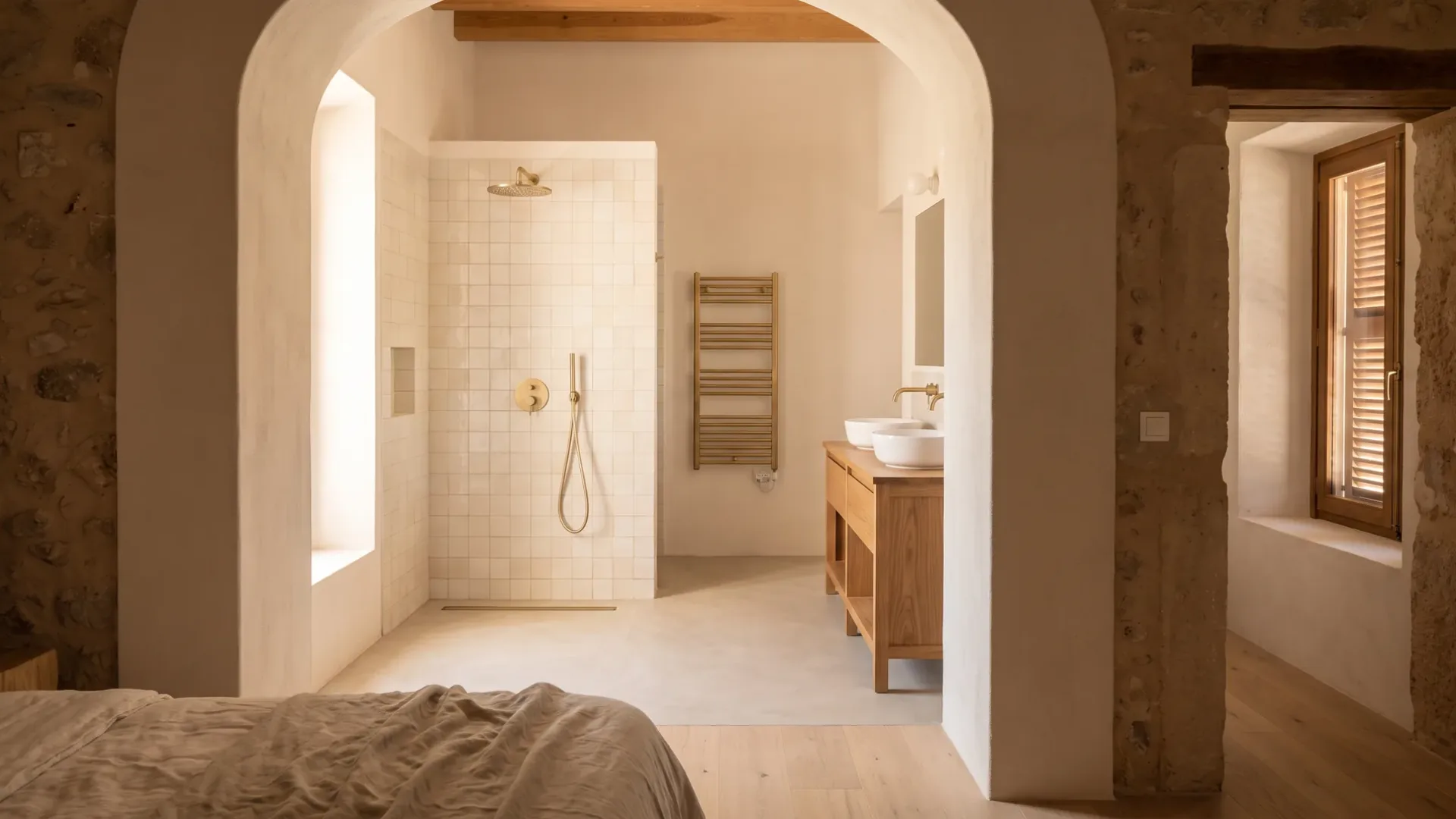 An archway opens from a bedroom onto a tiled shower recess with a heated towel rail and a double basin vanity beyond.