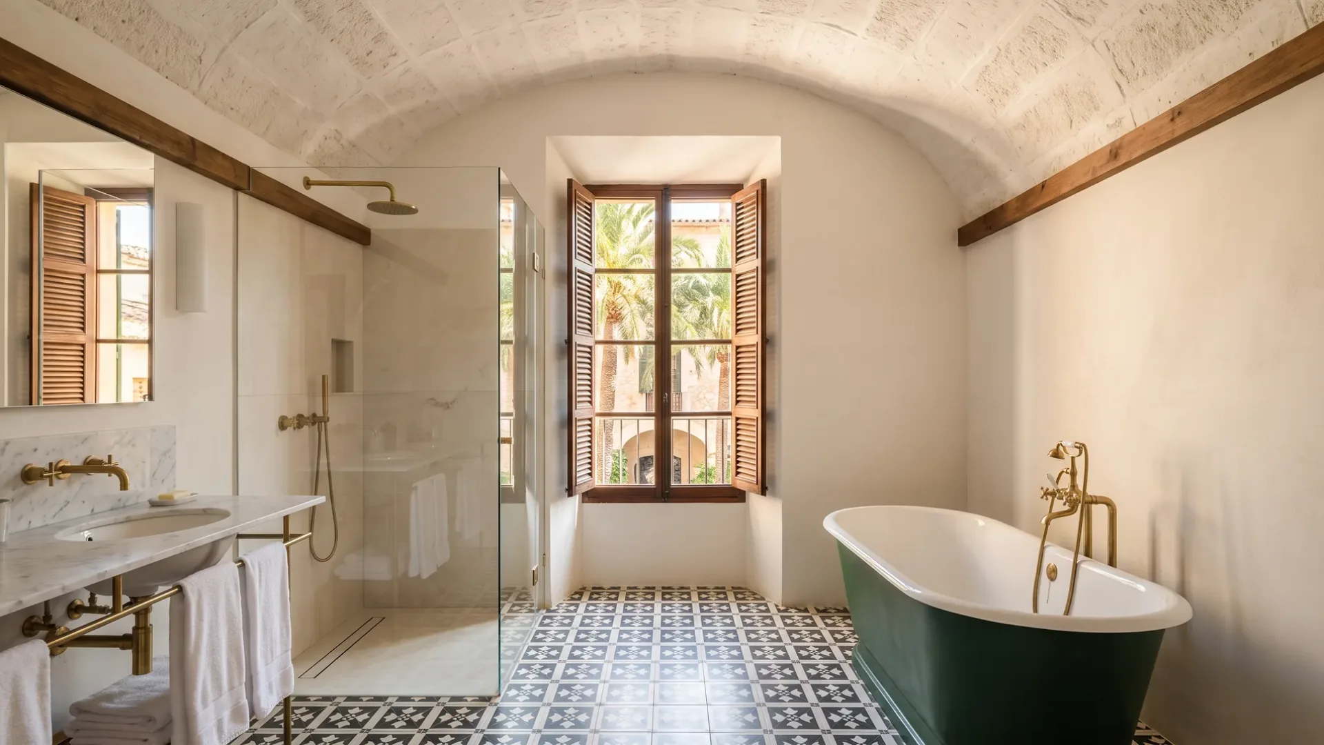 A vaulted ceiling rises over a glass shower and a green freestanding tub, beside a window onto palm trees and patterned tile.