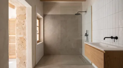 A bathroom pairs a plain microcement shower wall with white vertical tiles, black fittings and a floating wood vanity.