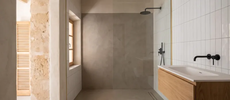 A bathroom pairs a plain microcement shower wall with white vertical tiles, black fittings and a floating wood vanity.
